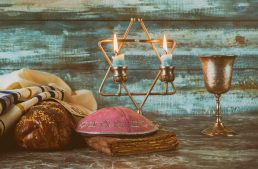 Shabbat eve table candles and cup of wine with covered challah bread,